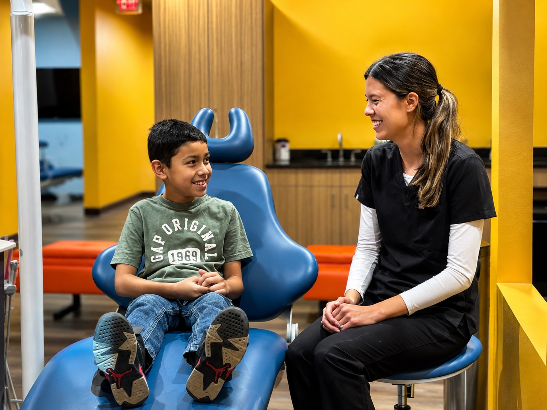 Boy In Dental Chair Talking With Staff Member