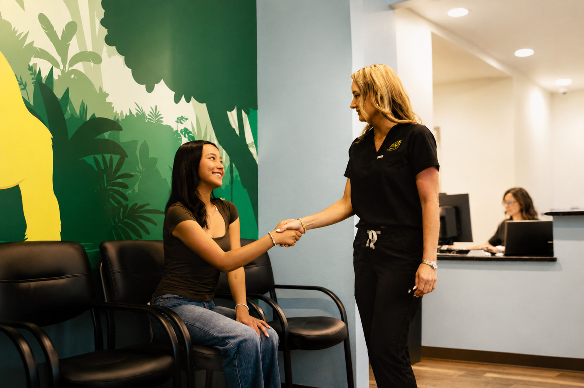 Staff Member Shaking Hands With Teen Patient In Waiting Room